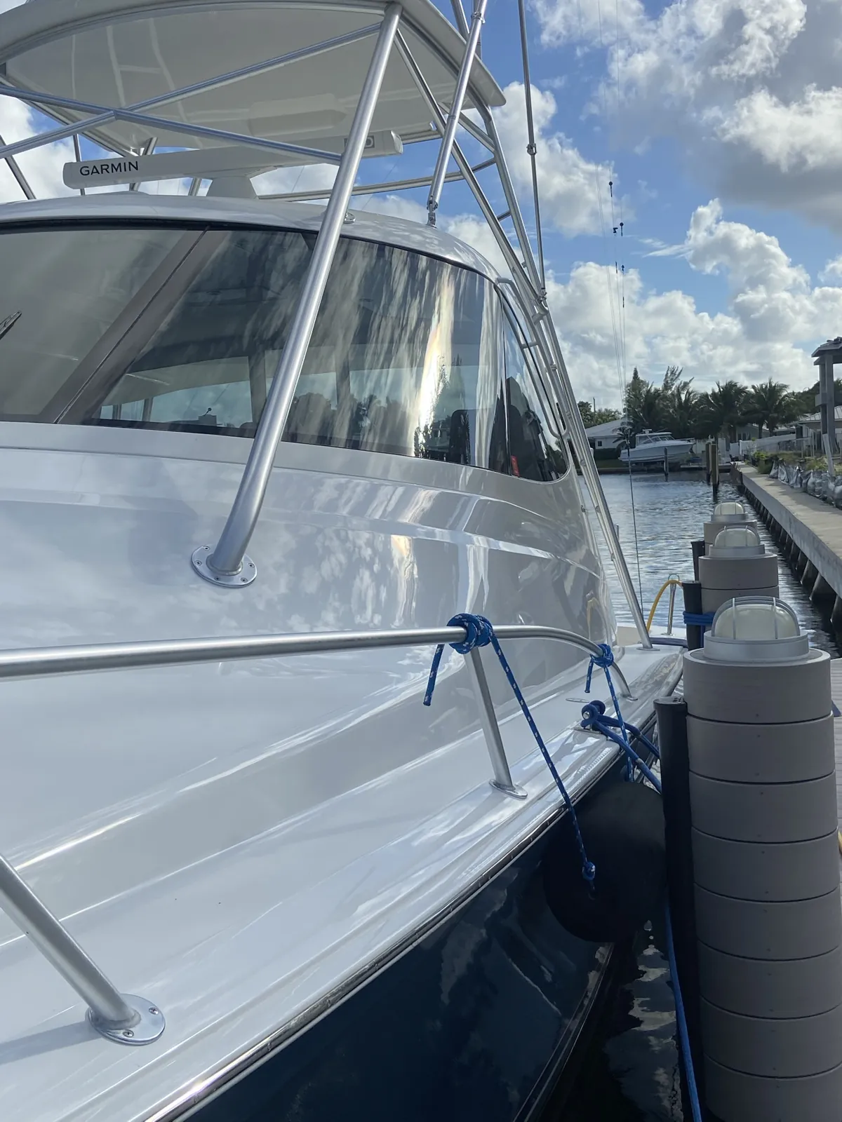 Glossy white sportfishing boat with a tower tied to a dock at Little Harbor in Deerfield Beach, FL after a detail