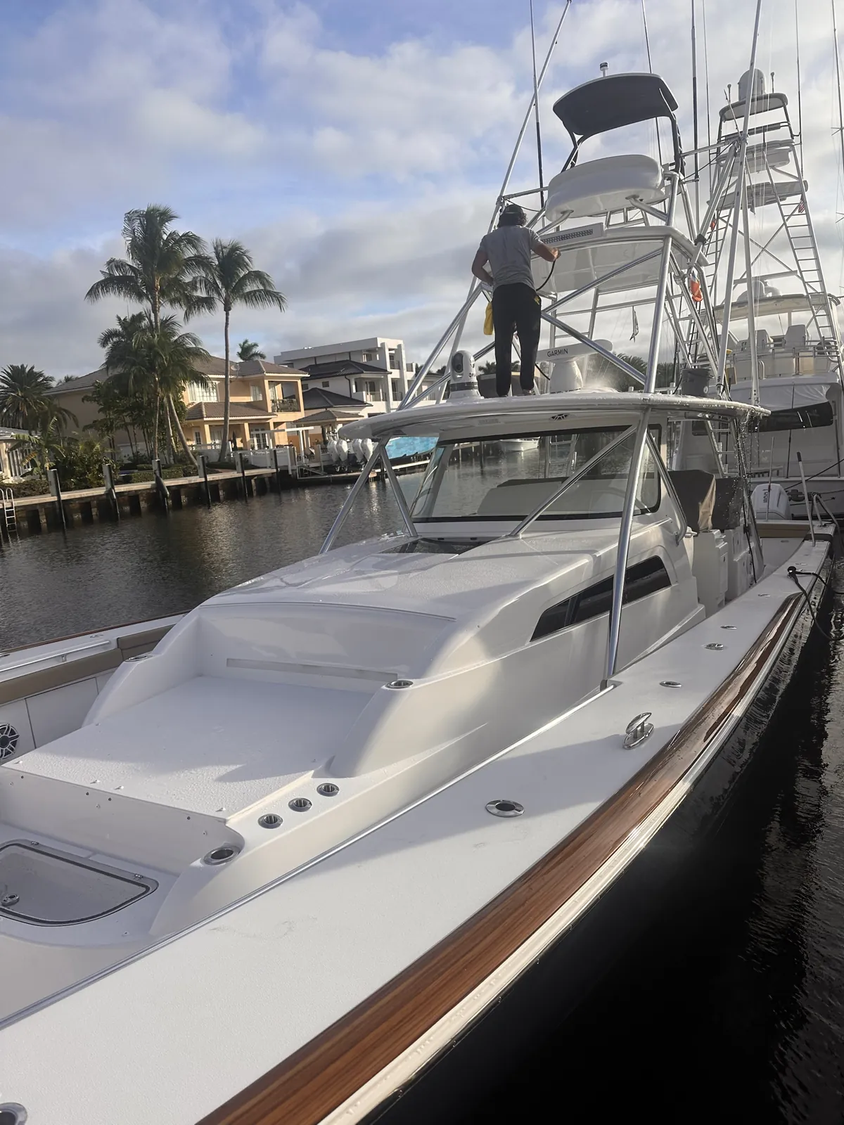 Detailer rinsing the tower of a sportfishing boat on a Las Olas canal in Fort Lauderdale, Florida