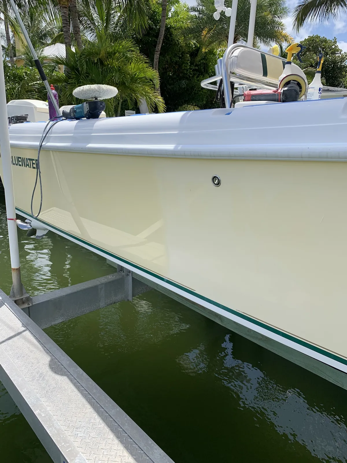 Cream Bluewater boat hull on a lift in Jupiter, Florida with buffers and a wool pad resting on the deck