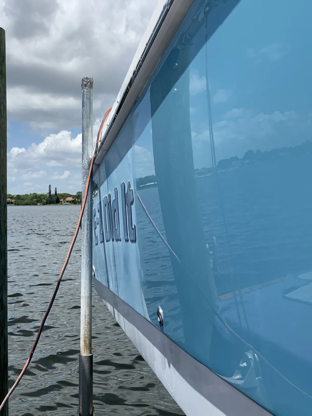 Light blue boat named E-Z Did It at a Jupiter, Florida dock with a glossy polished hull reflecting the sky and shoreline